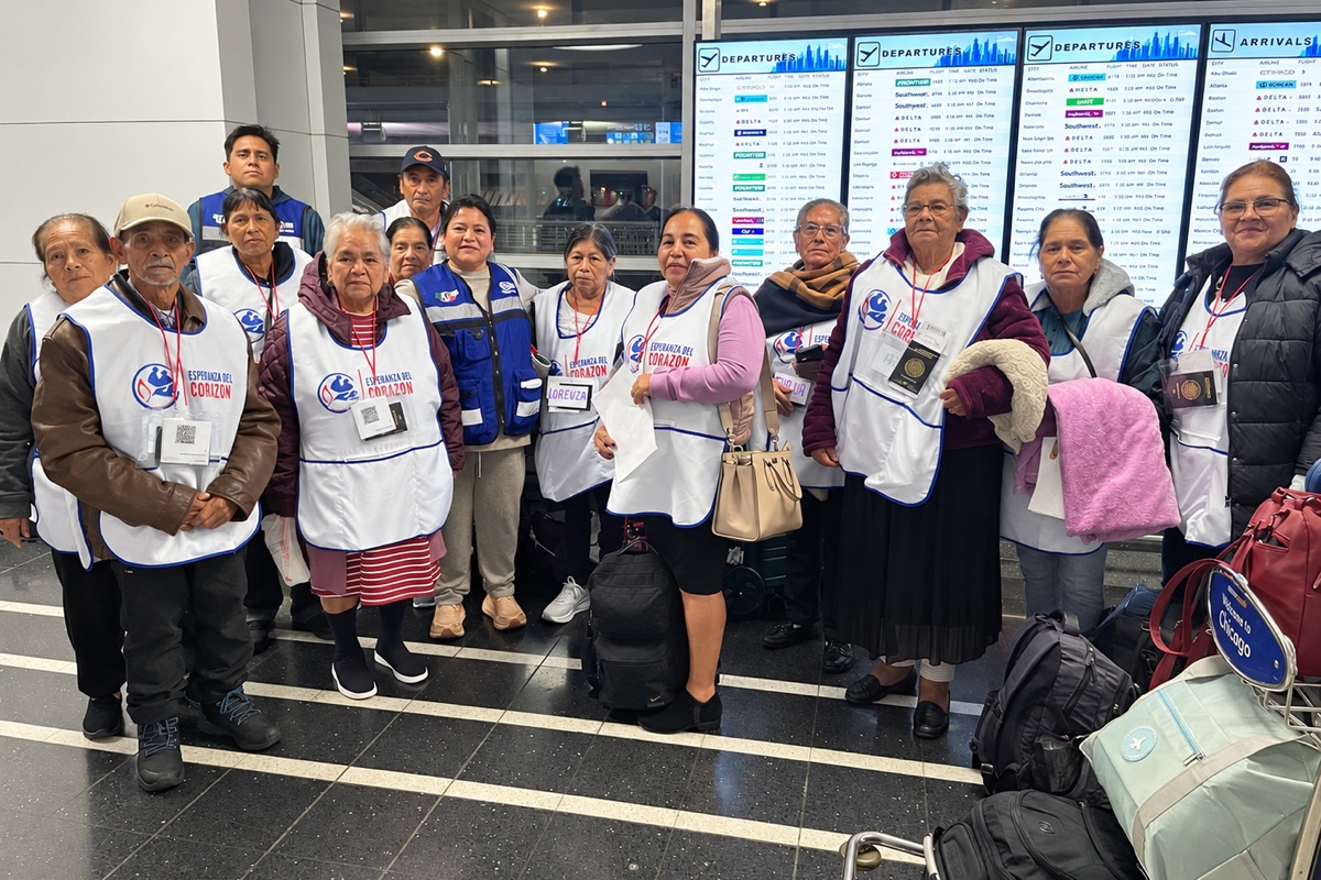 Grupo de participantes del programa con chalecos de Esperanza del Corazón frente a las pantallas de salidas de un aeropuerto
